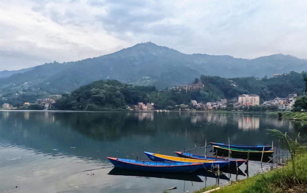 Colorful boats on Phewa Lake near Lakeside Pokhara with scenic mountain views in Nepal.